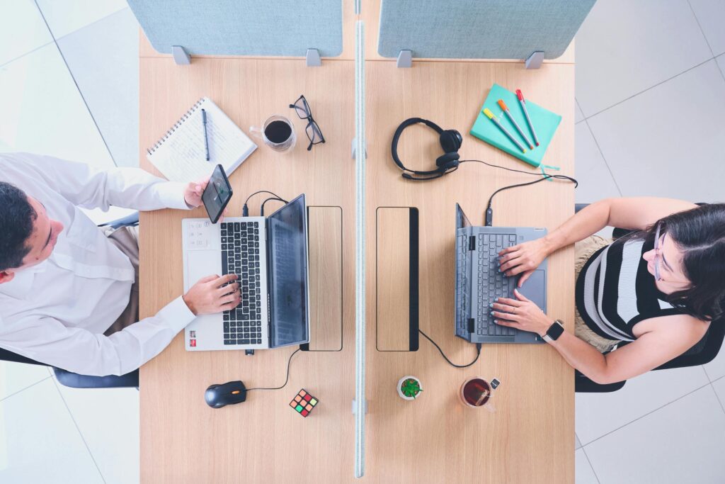 Top view of two people working on laptops across from each other illustrating body doubling and accountability for ADHD focus
