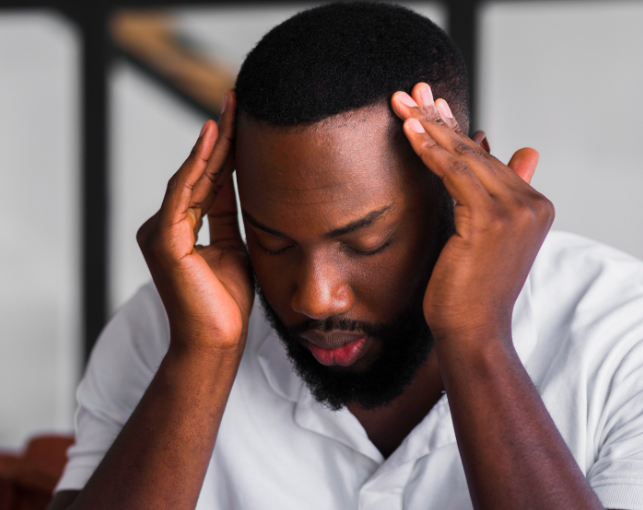Man holding his temples looking overwhelmed, representing ADHD decision paralysis and executive function overload.